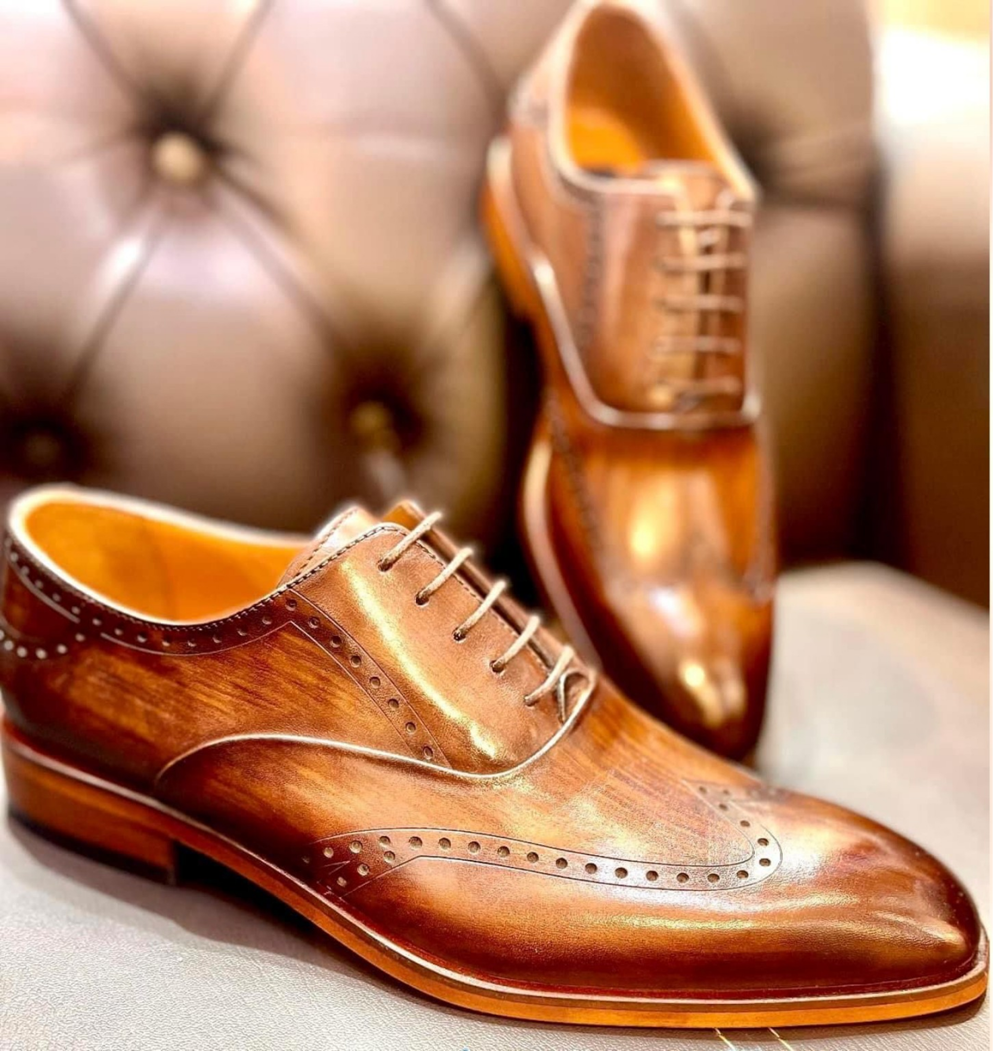 Brown leather dress shoes on leather chair.